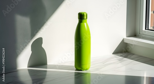 Vibrant Green Water Bottle Standing in Sunlight by a Window, Minimalist Aesthetic.