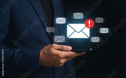 A person in a suit is holding a mobile device and a digital email sign