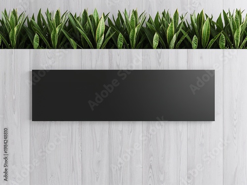 Long horizontal blank black signage board mockup on a white wood wall with green plants. Modern interior decor.
