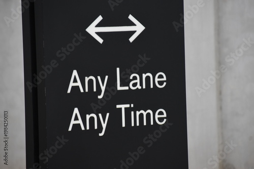 A black and white sign that says, Any Lane Any Time. Clear direction. Crowd management. Guide for people. Safety. 