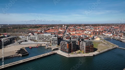 Aerial footage of Fredericia in Denmark with the harbor district, waterfront buildings, marina areas, and a historic cityscape of red-roofed houses and urban streets.