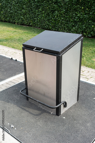 Wallpaper Mural Closeup Stainless Steel Charger Cabinet Detail With Handle And Cable, Showing Hinge And Lock Plate On Textured Metal Panel, Asphalt Base And Manicured Hedge Emphasize Tidy, Secure Public Installation. Torontodigital.ca