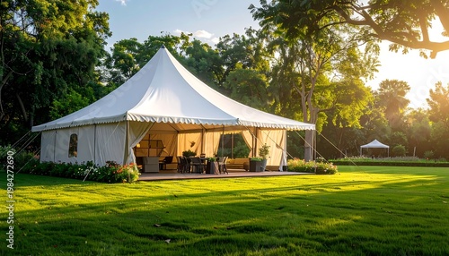 Large white event tent on green lawn surrounded by trees, sunlit open view