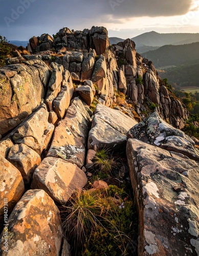 Rocky outcrop at sunset, boulders dominate foreground with distant mountains, warm light