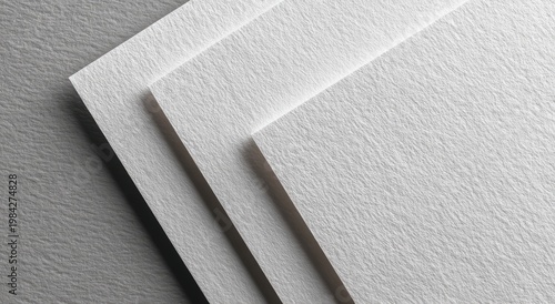 A close-up shot showcases a stack of textured white paper, subtly illuminated by soft light, highlighting its surface details and creating a minimalist aesthetic.