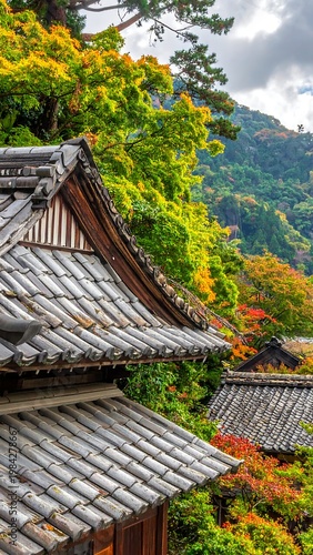 Japanese rooftop tiles in autumn, surrounded by colorful trees on a hillside backdrop