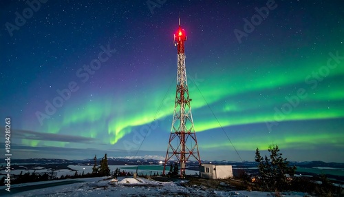Antenna tower on snowy hill under aurora borealis, distant mountains