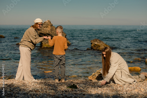 mother, son and daughter spending time together on sea beach in spring
