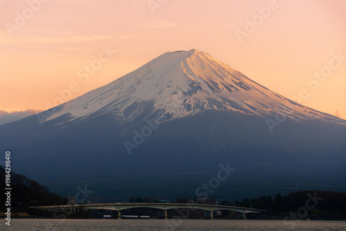 Golden sunrise over Mount Fuji with snow-capped peak and Kawaguchiko bridge, Japan.