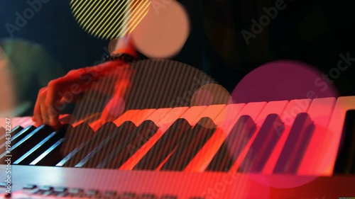 Forearm entering frame, keyboardist pressing keys and alternating chords for music, bokeh rising