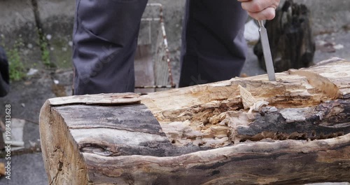 Woodworking carving, crafts-person digging tree trunk using hammer and chisel