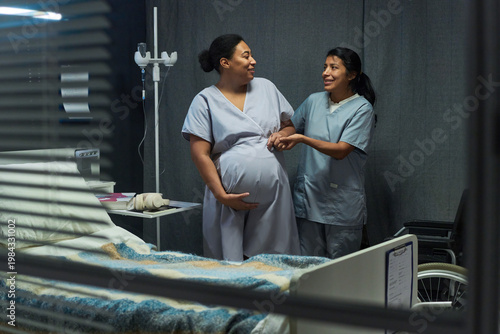 Cuadro en lienzo Medium shot of pregnant woman receiving support from nurse in hospital room, holding belly and smiling