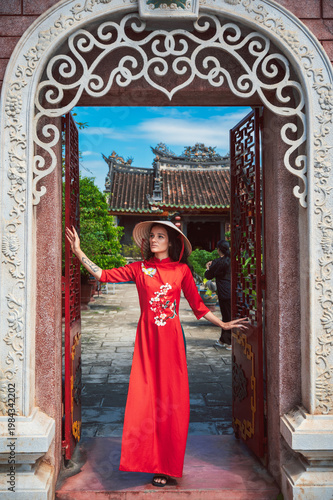 Portrait of a tourist in a hat and a traditional Vietnamese dress against the background of a Buddhist temple in Hoi An.