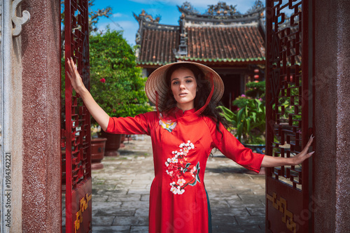 Portrait of a tourist in a hat and a traditional Vietnamese dress against the background of a Buddhist temple in Hoi An.