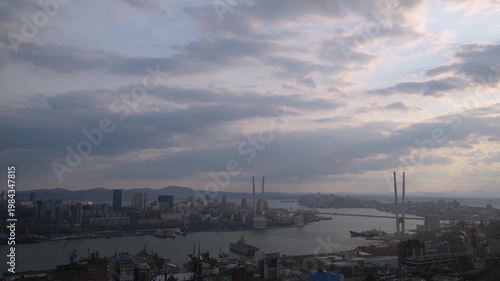 Timelapse city harbor at dusk with dramatic cloudscape and bridge silhouettes.
