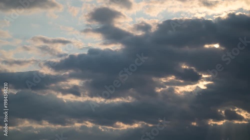 Time-lapse view of dramatic clouds with shifting light effects in the sky.
