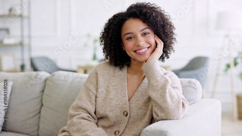 Smiling woman with curly hair sitting on couch