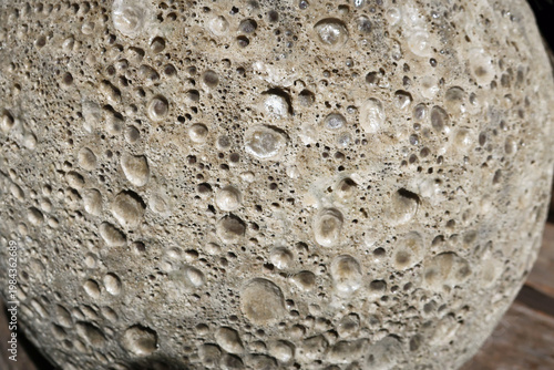 Fotografie Weathered, distressed grey concrete ceramic sphere, with lunar or moon like cratered pitted or pock marked surface texture