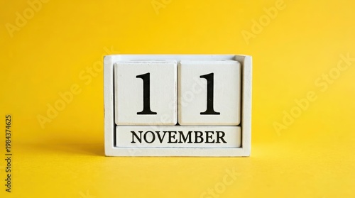 Wooden block calendar showing november eleventh date on yellow surface.