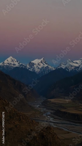 A majestic snow-capped mountain range glowing in the golden light of sunrise