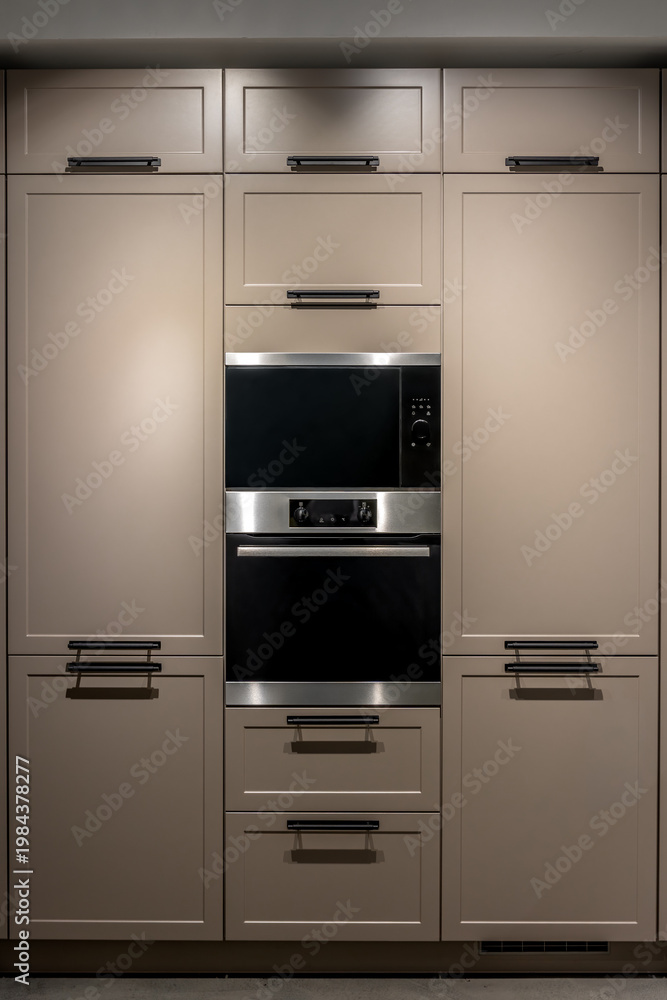 Fototapeta premium Built in kitchen with oven in beige cabinets modern interior. Minimalist kitchen furniture design.