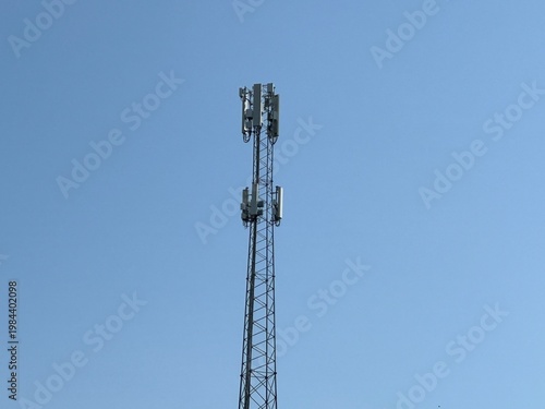 Cell tower with antennas against a clear blue sky