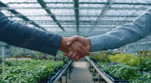 Business people shaking hands in greenhouse with plants and rows of seedlings