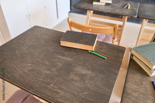 Obraz na plátně Wooden classroom desks with books and pencils in well-lit minimalist study space