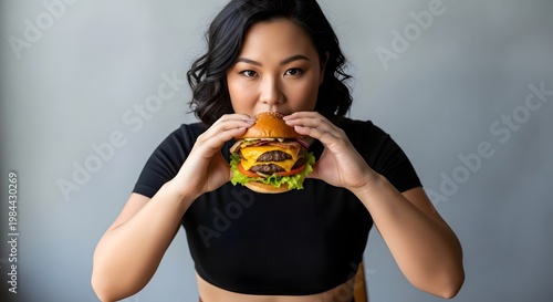 Woman eating delicious burger indoors with focus on food and expression