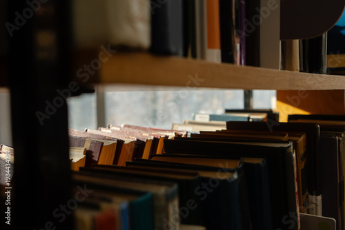 Foto Old books on the bookshelf in library archive interior in sunny day