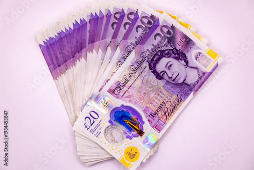 A stack of twenty pound banknotes from the Bank of England featuring Queen Elizabeth II, isolated on white background