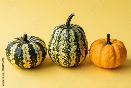 Three small white pumpkins sitting next to each other on a yellow background
