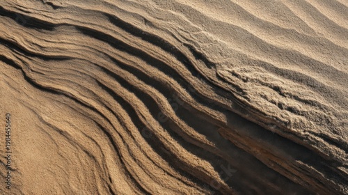 Layered sandstone with wavy patterns in brown and black, sculpted by nature, light showcasing texture.