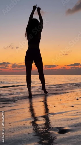 Slim woman in bikini standing on beach at sunset with ocean reflection in Maldives. Concept of travel, relaxation, summer, tropical lifestyle, freedom, vertical video.