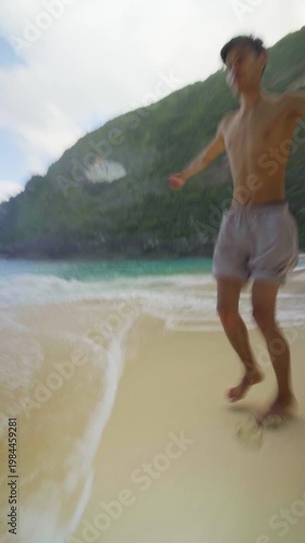man running on the beach Kelingking cliffs on Nusa Penida, Bali, enjoying ocean waves and tropical scenery.