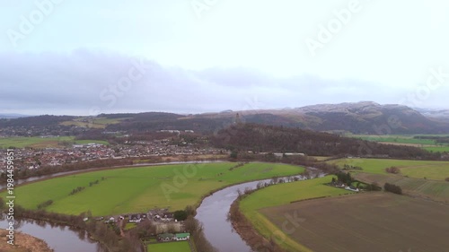 Stirling Scotland city skyline and Forth River drone flyover and mountains in the distance. Clouds cover the sky, creating an atmosphere in the Scottish highlands