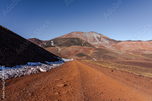 Dirt road to colorful mountain landscape with snow patches
