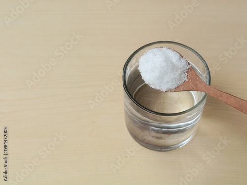 Φωτογραφία Glass of salt water solution with salt on wooden spoon on wooden table