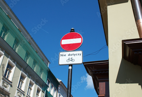 Low angle view of a no entry traffic sign with additional plate allowing bicycles, reading “Nie dotyczy,” on a sunny day in a European Polish city. Krakow in Poalnd. 