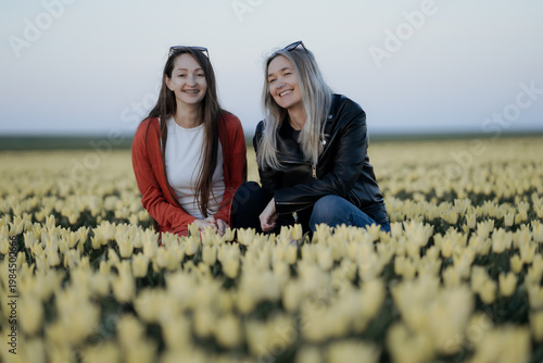 two beautiful Women standing in colorful tulip flower fields in Amsterdam region, Holland, Netherlands. Magical Netherlands landscape with tulip field in Holland Trevel and spring concept