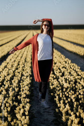 Beautiful Woman standing in colorful tulip flower fields in Amsterdam region, Holland, Netherlands. Magical Netherlands landscape with tulip field in Holland Trevel and spring concept