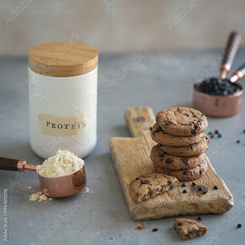 Protein cookies with chocolate chips and protein powder on wooden board, healthy snack concept in home kitchen setting, High protein snack recipe. food blog or fitness recipe inspiration