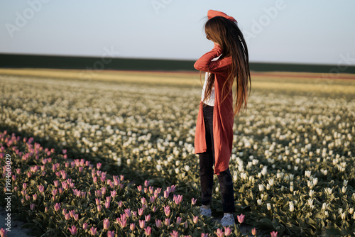 Beautiful Woman standing in colorful tulip flower fields in Amsterdam region, Holland, Netherlands. Magical Netherlands landscape with tulip field in Holland Trevel and spring concept