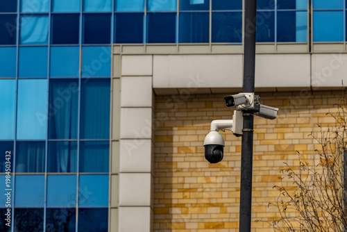 Fotografie A specialized video surveillance camera hung on a tall pole next to a public bui