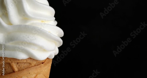 Vanilla ice cream in a waffle cone close-up on a turntable. Close-up footage on a black background.