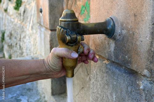 Main faisant couler l'eau d'un robinet en cuivre dans une rue en gros plan