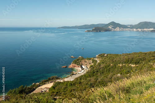 Coastal panorama with blue sea and bay, grassy hillside overlooking shoreline, Mediterranean landscape, scenic travel destination, summer nature background