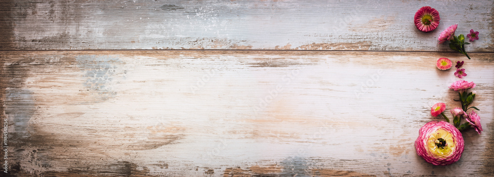 Fototapeta premium Purple flowers on vintage wooden background. Top view of rustic wooden banner with space for text. Ideal for a mother's day greeting card.