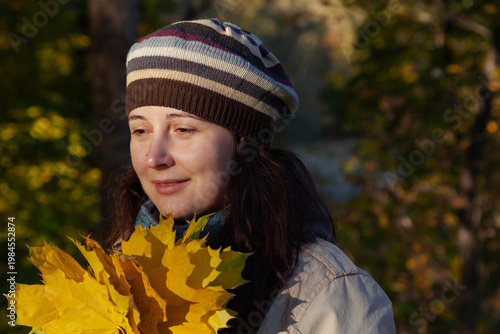 Woman in autumn park with large leaves in her hands