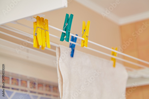 Different colored plastic clothespins hang on dryer